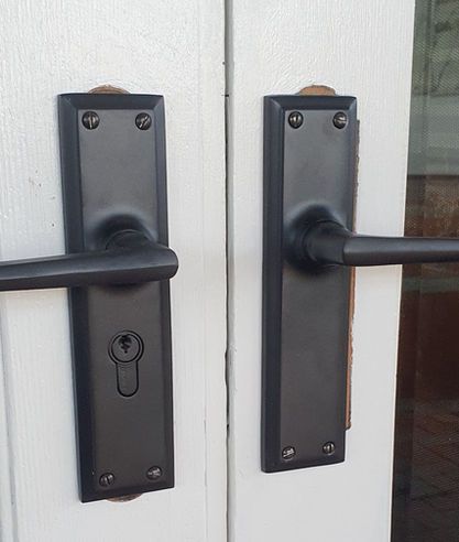 A pair of black door handles on a white door.