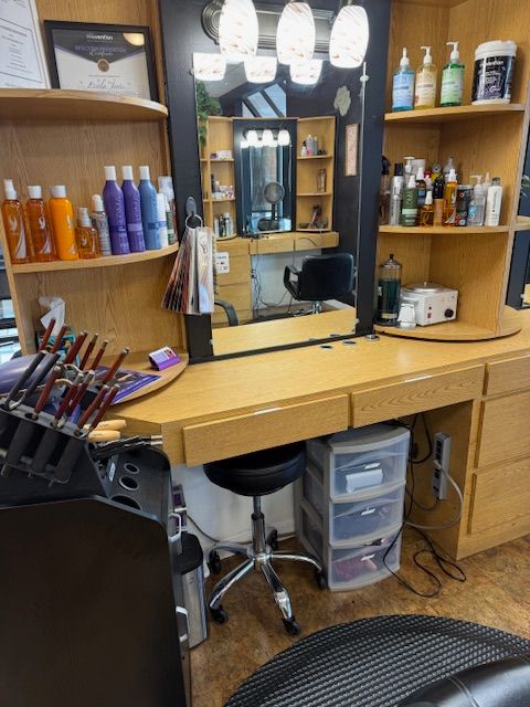 Hair salon station with mirror, products, and chair.