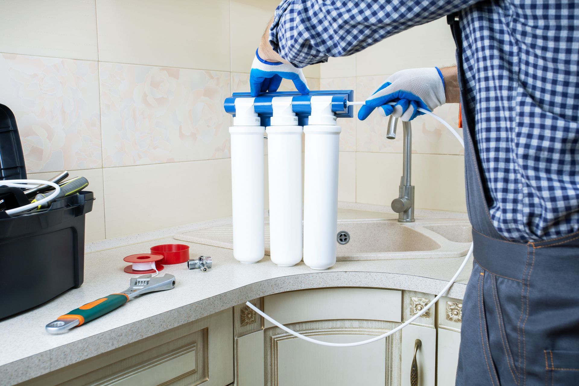 A man is installing a water filter in a kitchen.