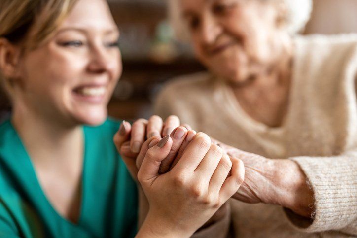 senior woman holding hands with a nurse