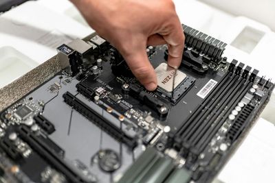 A person's hand carefully places a CPU onto a black computer motherboard socket.