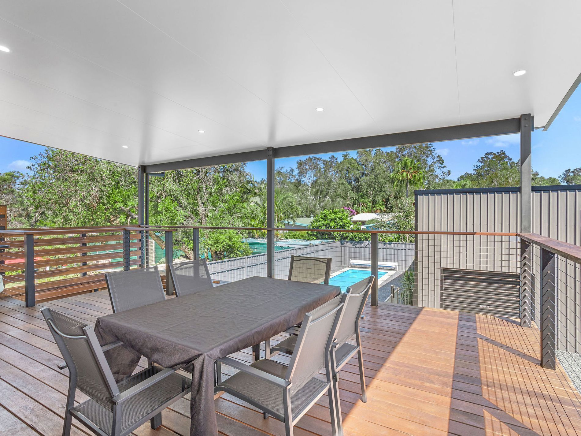 Covered outdoor patio with dining table, chairs, and a pool view — Wade Adams Constructions in Forster, NSW