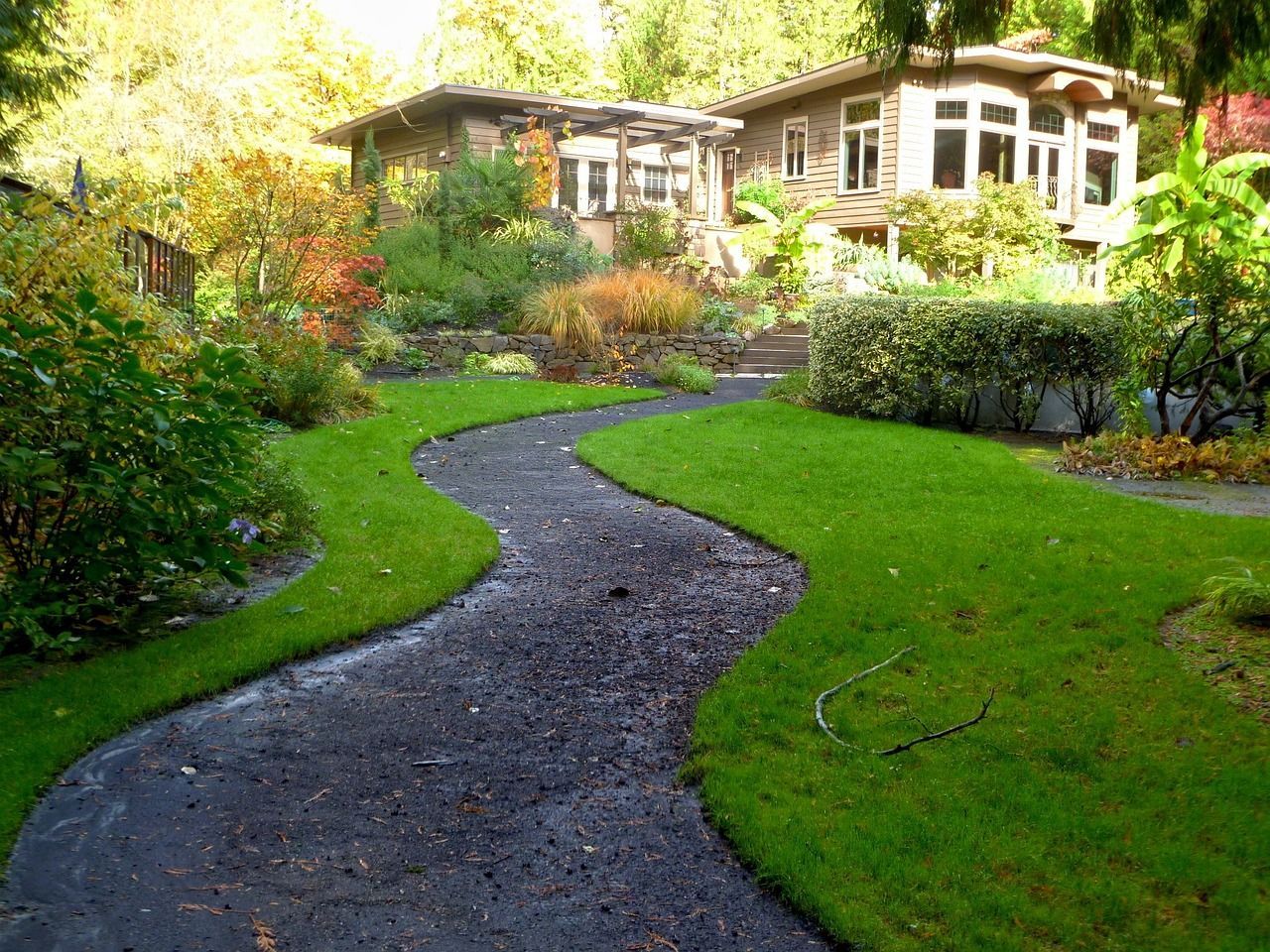a path leading to a house in a lush green garden