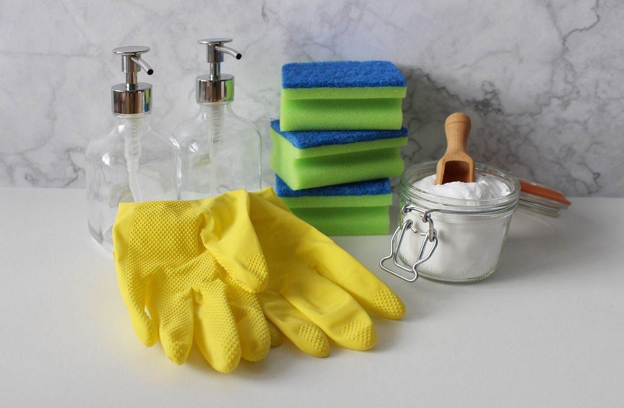 a table topped with cleaning supplies including gloves , sponges , soap dispensers and baking soda