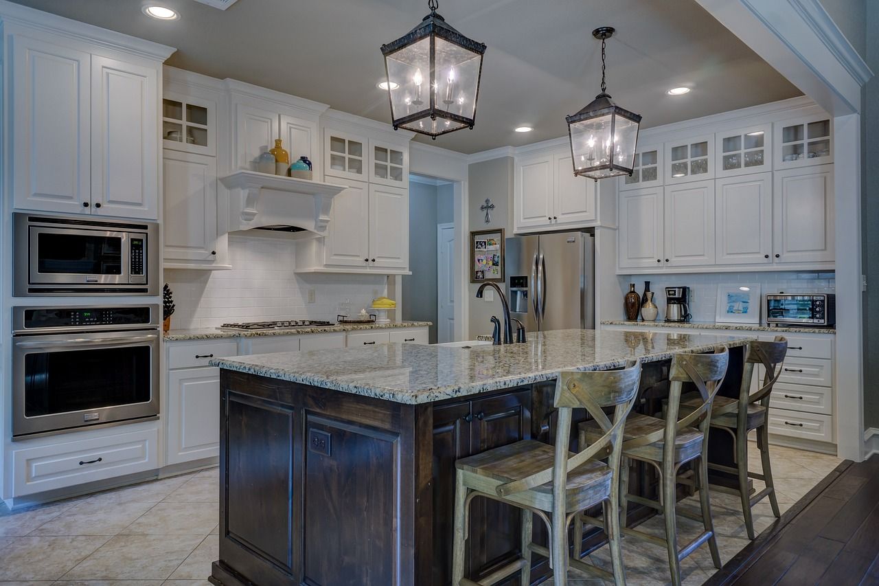 a kitchen with white cabinets , granite counter tops , stainless steel appliances and a large island