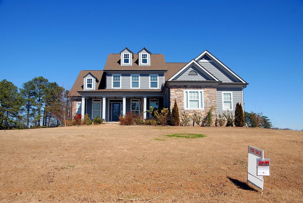 a large house with a for sale sign in front of it