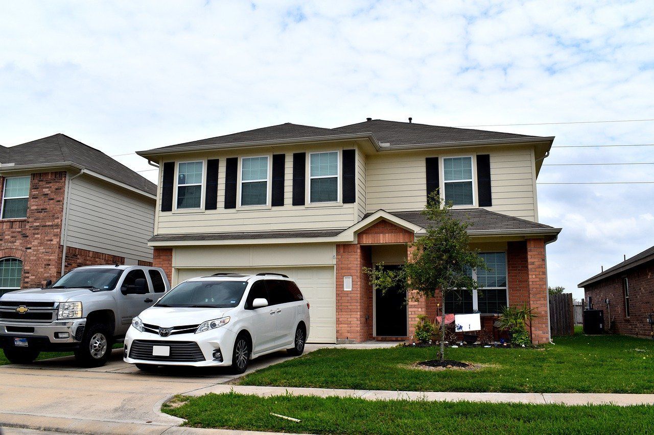 two cars are parked in front of a large house