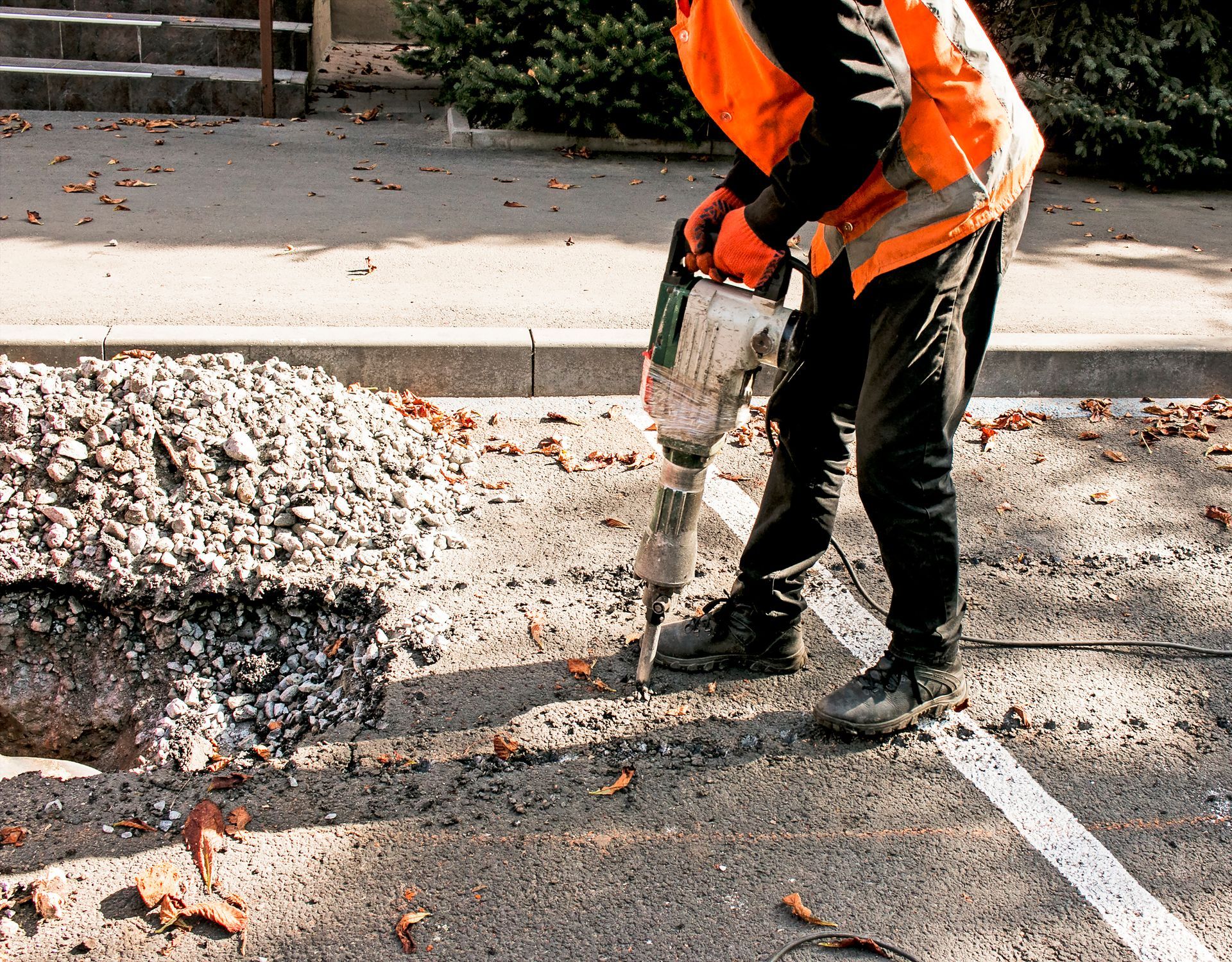 A man is using a hammer to drill a hole in the ground