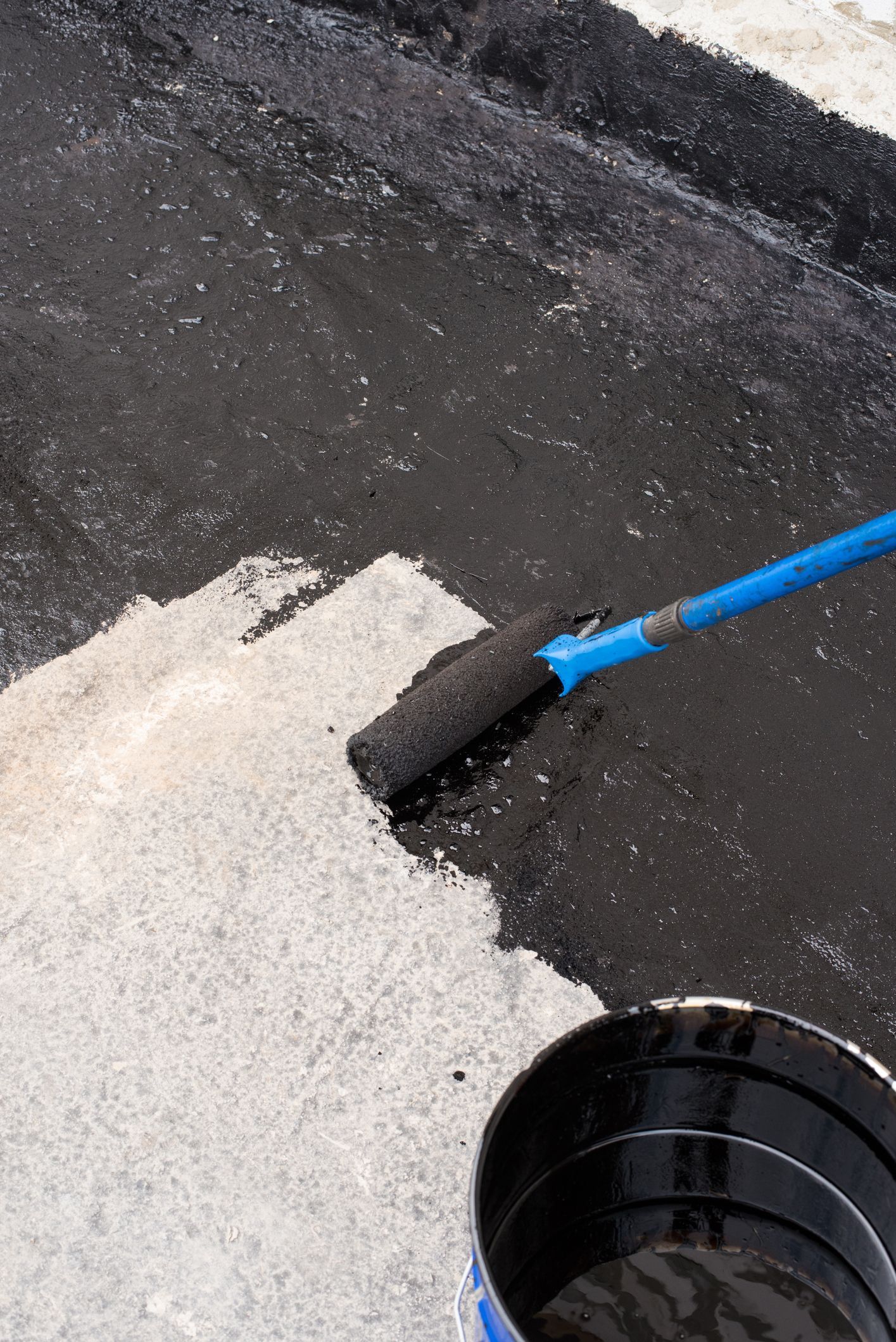 A person is painting a concrete surface with a roller.