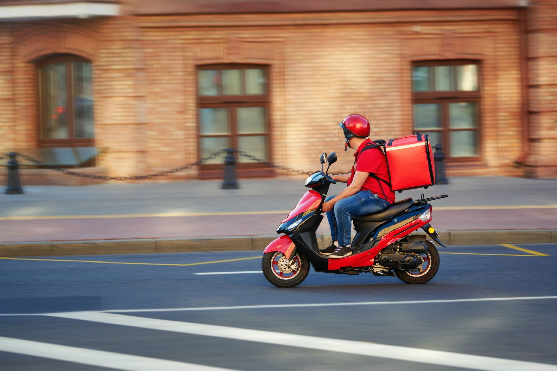 a delivery man is riding a scooter down a city street