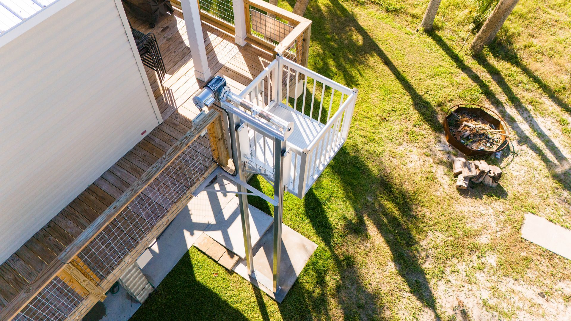 Outdoor platform lift next to a house, on a grassy lawn.