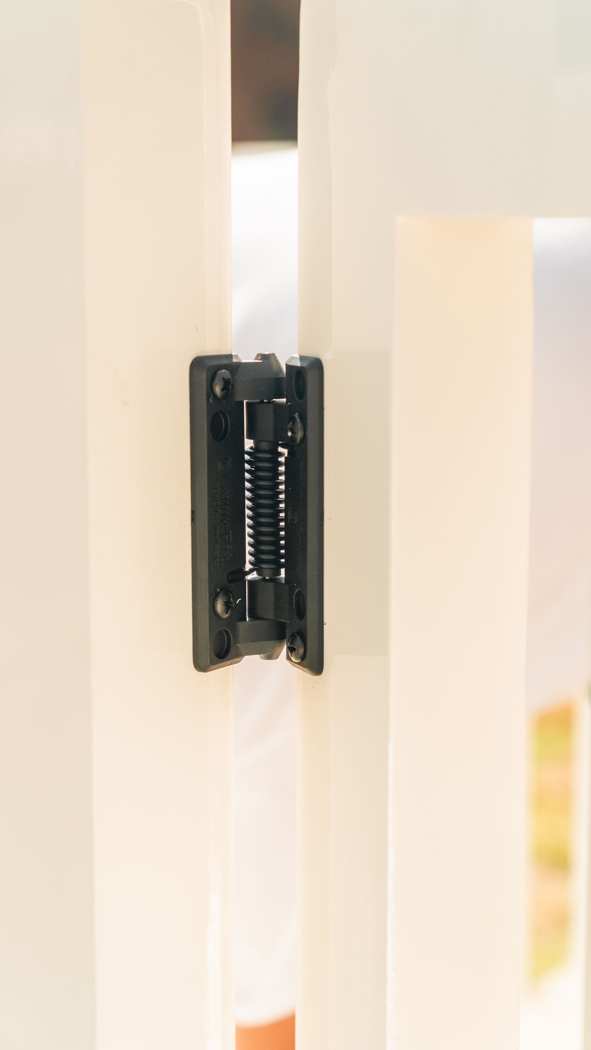 Black spring-loaded mechanism installed between two white door panels.