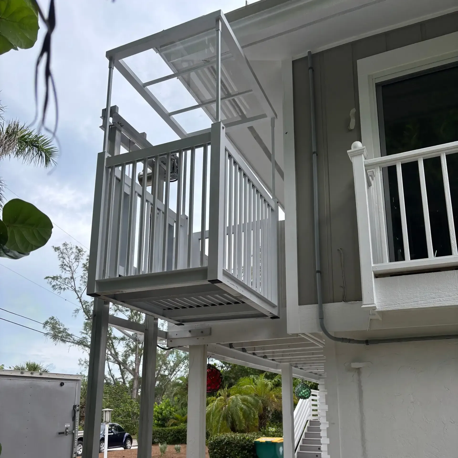 Wheelchair lift installed on a two-story building's exterior, white and gray.