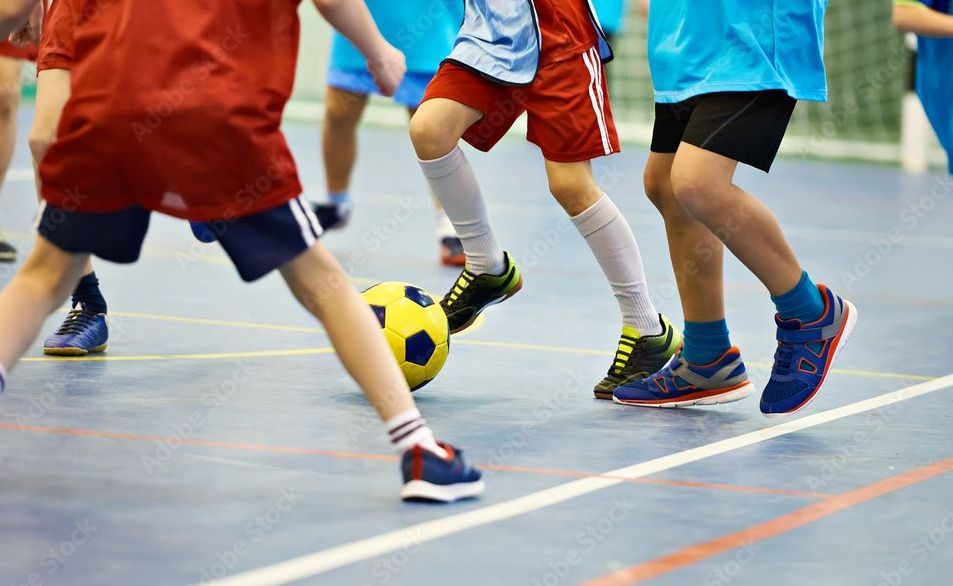 young soccer players competing for the soccer ball in an indoor gymnasium