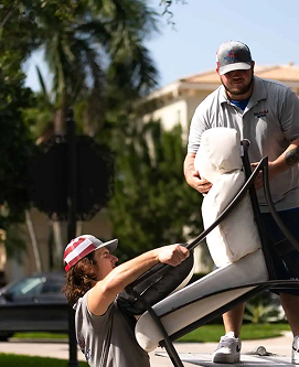A man is holding a chair while another man stands behind him