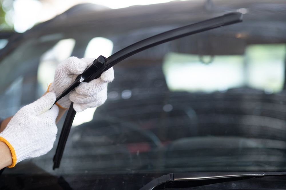 Person in gloves attaching a windshield wiper blade to a car.