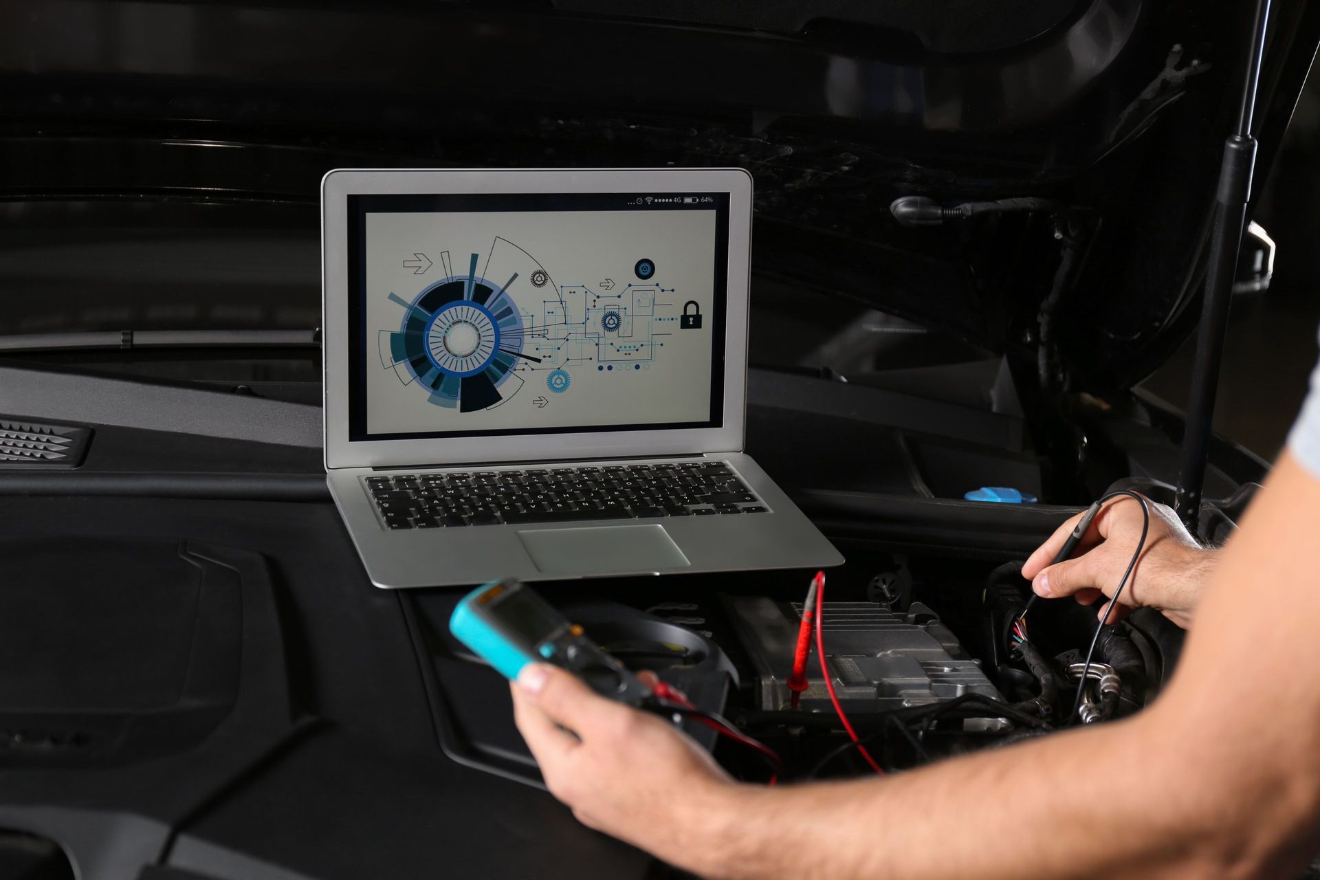 A mechanic uses a digital multimeter and a laptop to diagnose a car’s electrical system.
