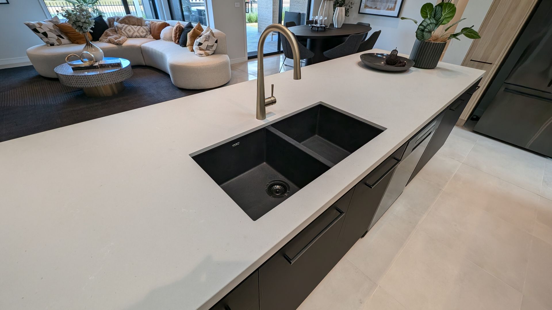 A kitchen with a black sink and a white counter top.