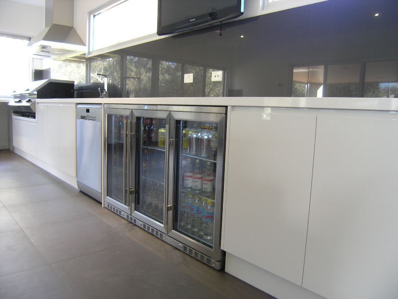 A kitchen with white cabinets and a stainless steel refrigerator