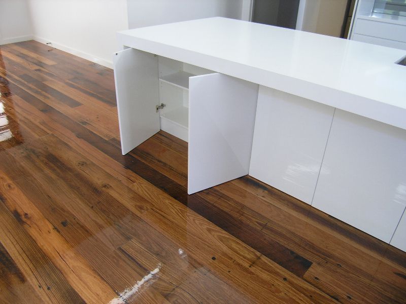 A kitchen with wooden floors and white cabinets with the doors open.