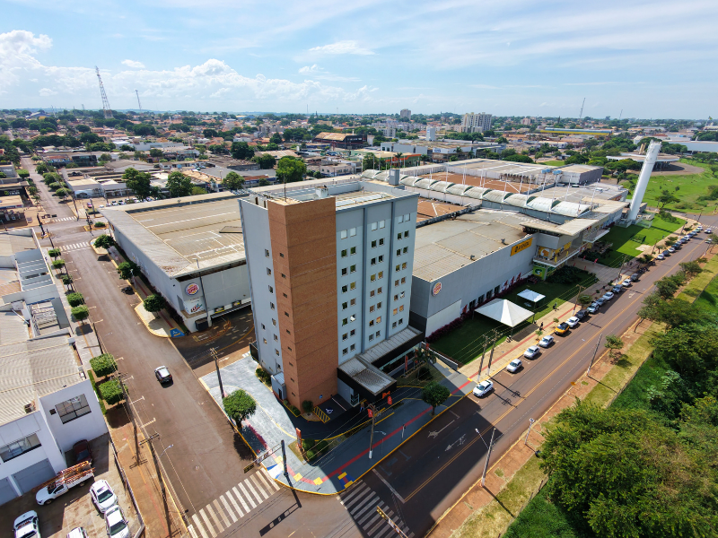 Vista aérea do Hus Hotel Dourados em localização privilegiada, ao lado do Shopping Avenida Center, destacando o fácil acesso e a infraestrutura urbana da cidade.