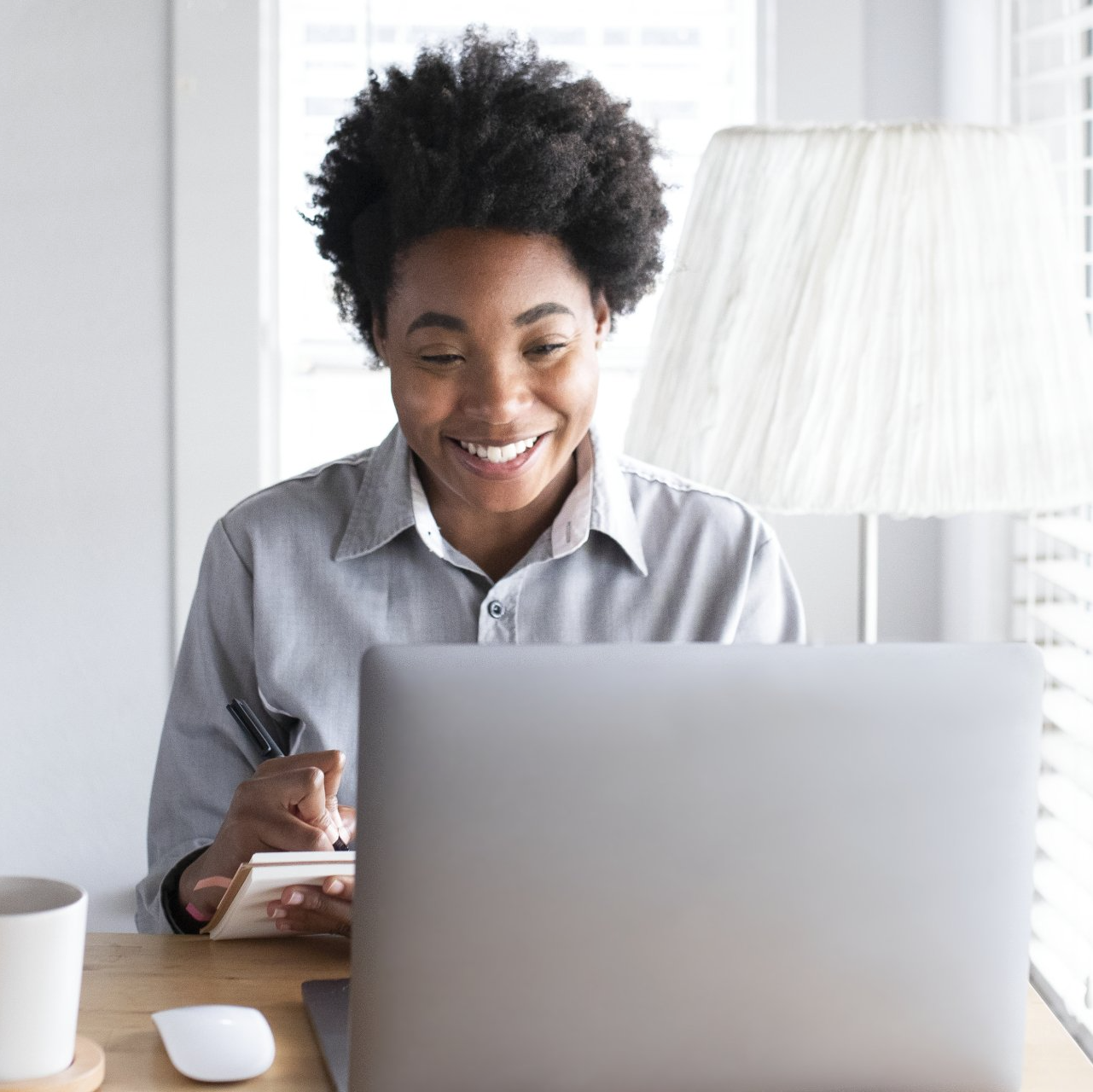 A woman is smiling while using a laptop computer.