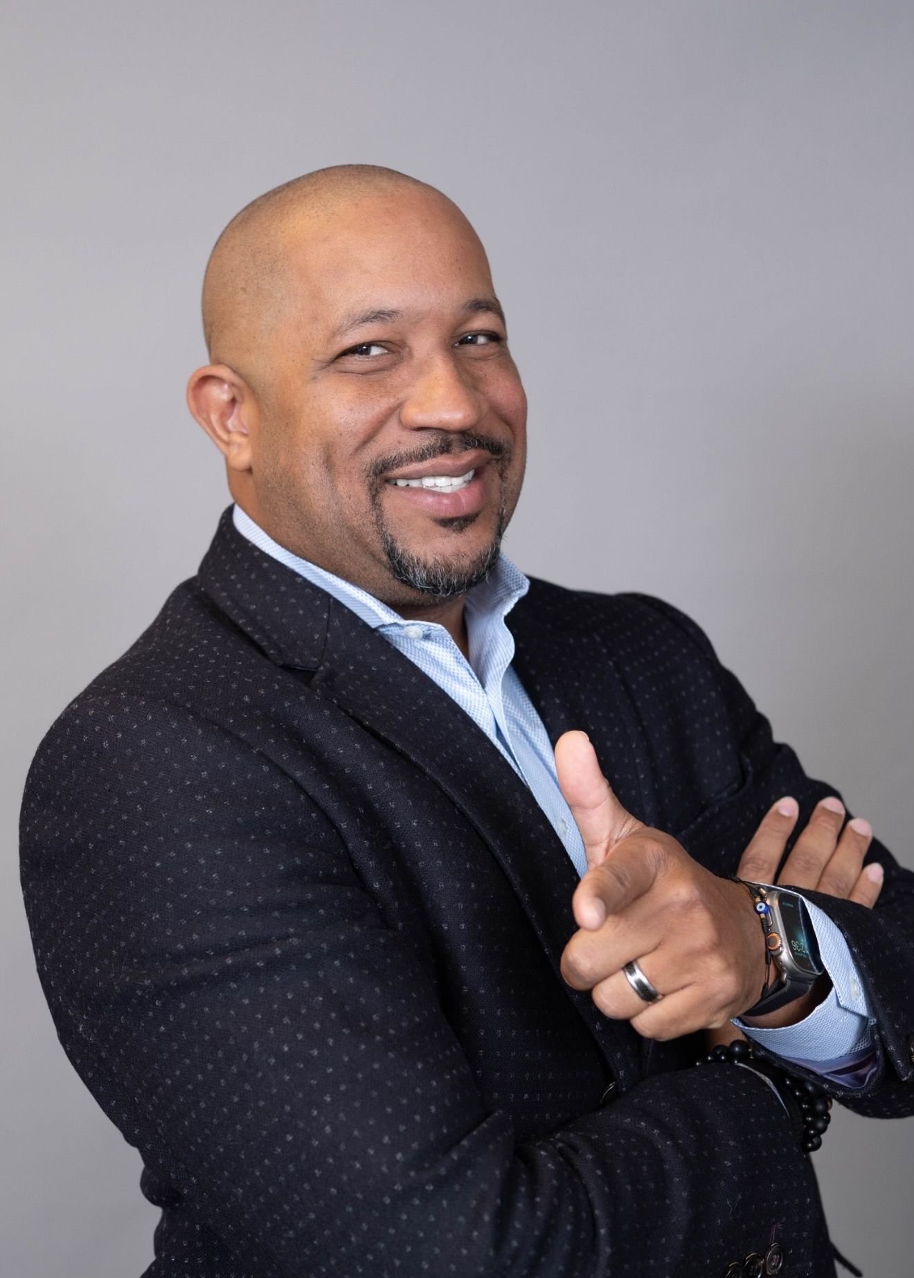 A man in a suit is smiling and giving a thumbs up.