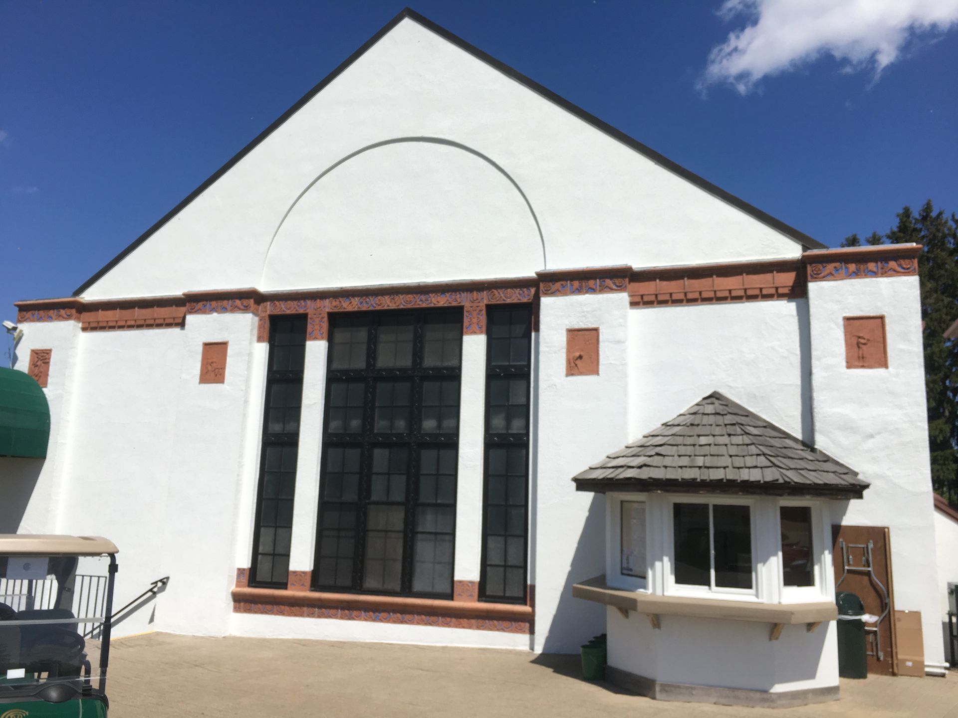 A white building with a green golf cart parked in front of it