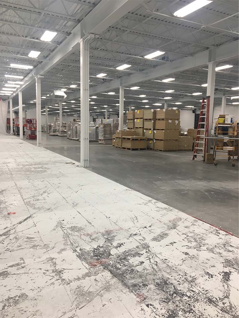 A large white building with a lot of windows is sitting on top of a lush green field.