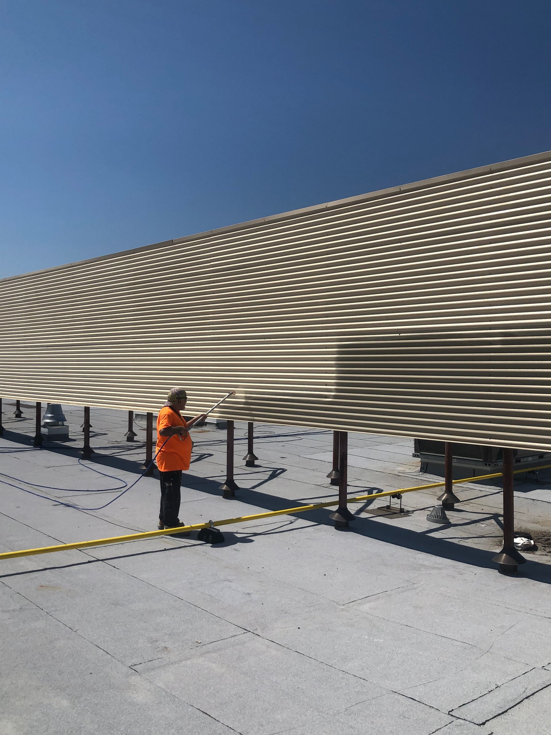 A man in an orange vest is standing in front of a building