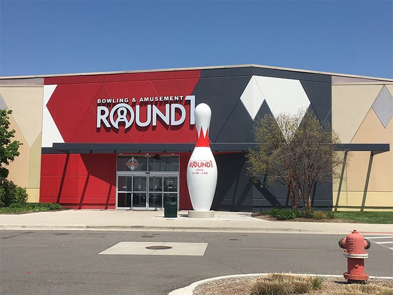 A bowling alley with a large bowling pin in front of it.