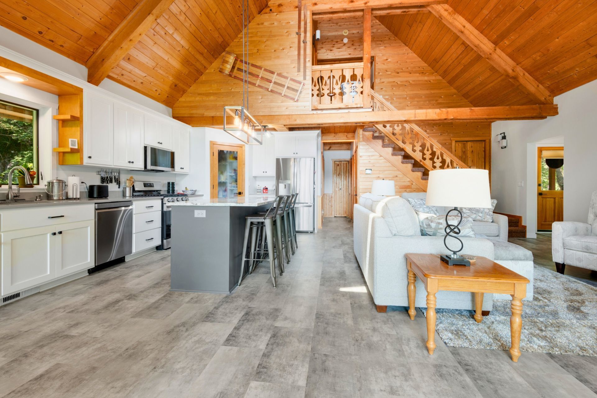 A living room and kitchen in a house with a wooden ceiling.