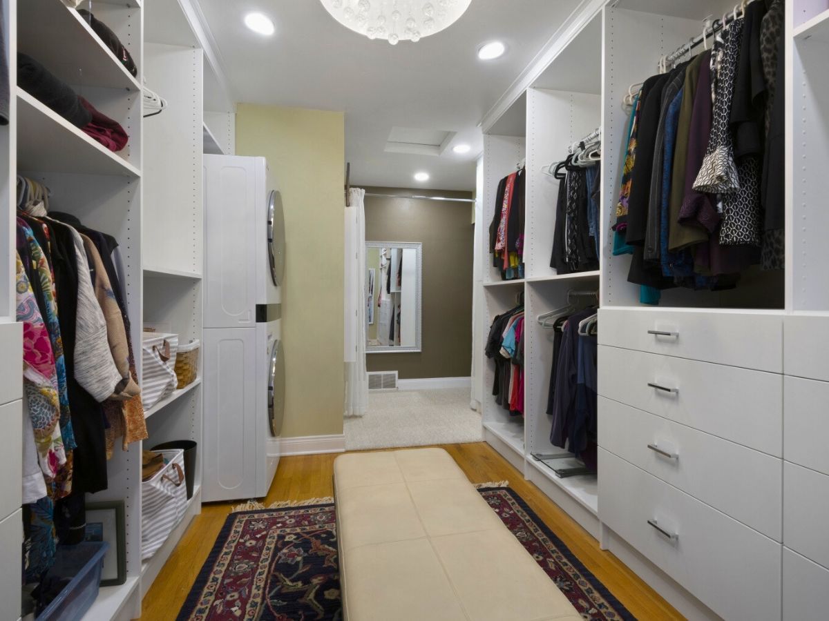A walk in closet filled with clothes and a bench