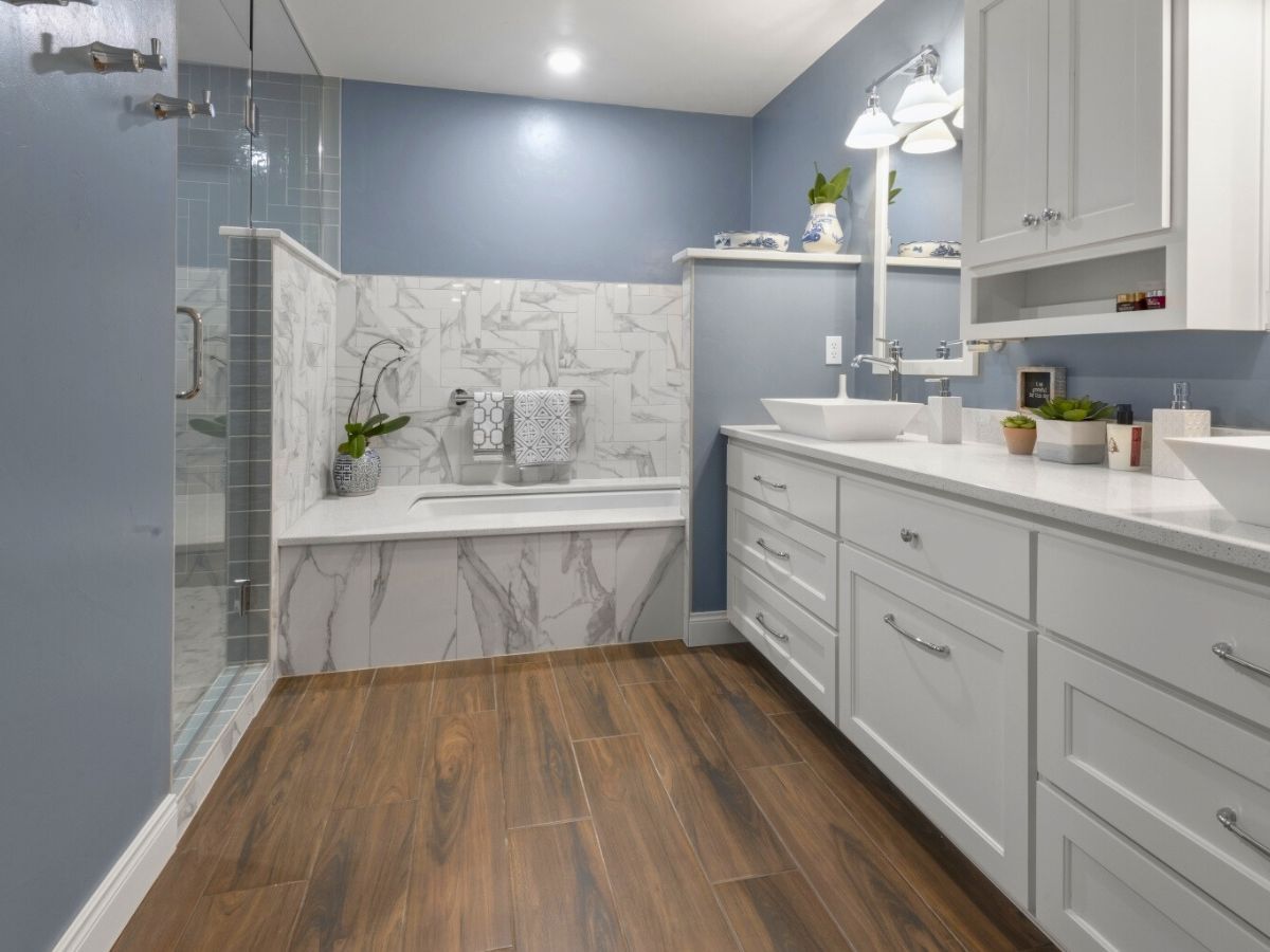 A bathroom with two sinks , a tub , and a walk in shower.