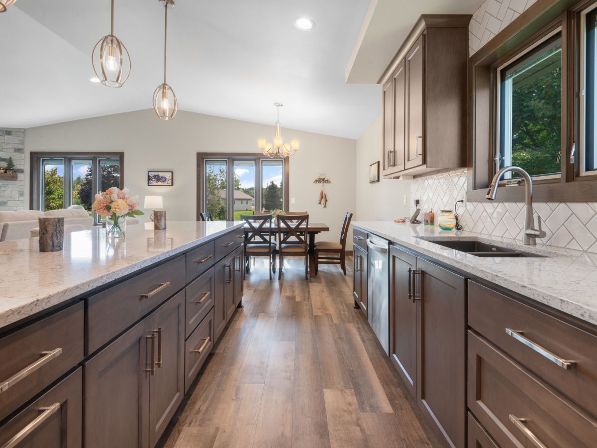 A kitchen with a sink , cabinets , and a dining room in the background.