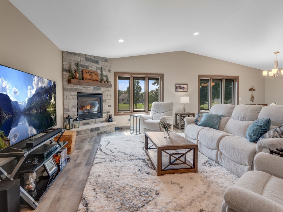 A living room with a couch , chairs , a fireplace and a flat screen tv.