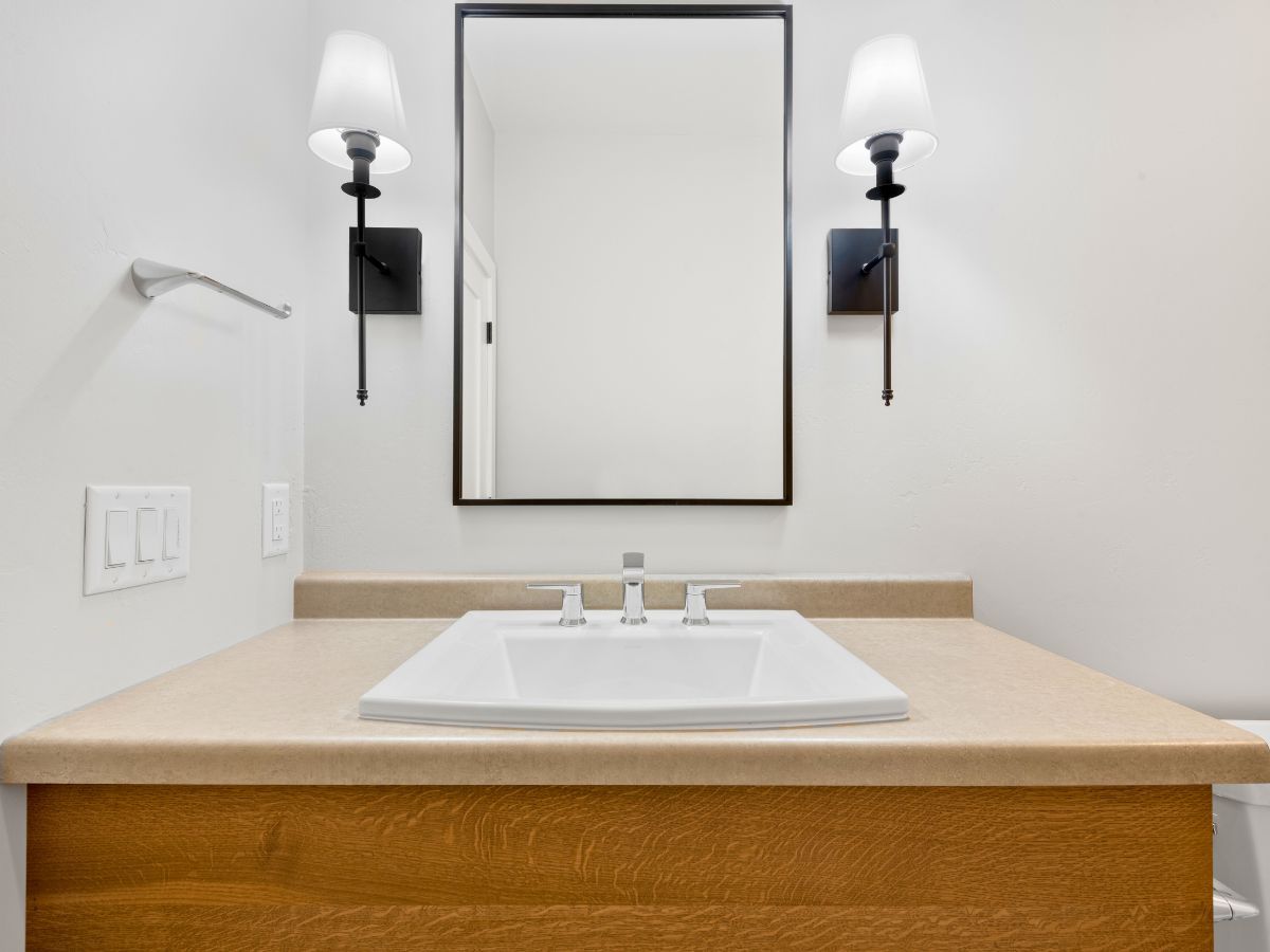 A bathroom with a sink , mirror and two lights.