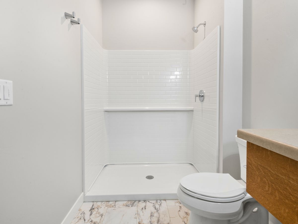 A bathroom with a toilet , shower and sink.