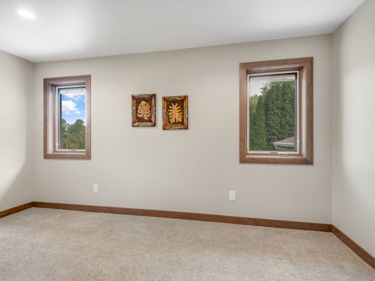 An empty room with three windows and two paintings on the wall