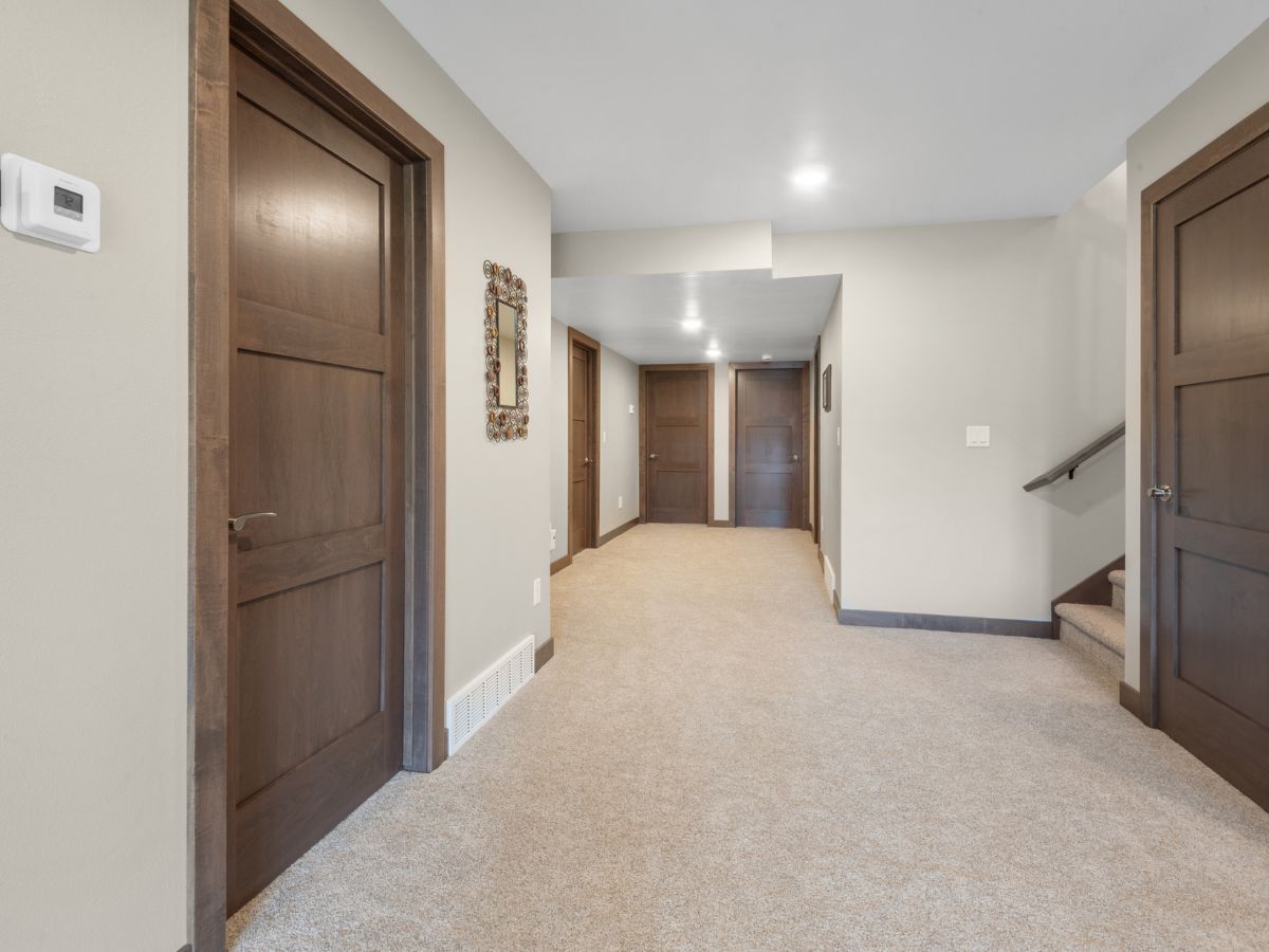 A hallway with carpeted floors and wooden doors in a house.