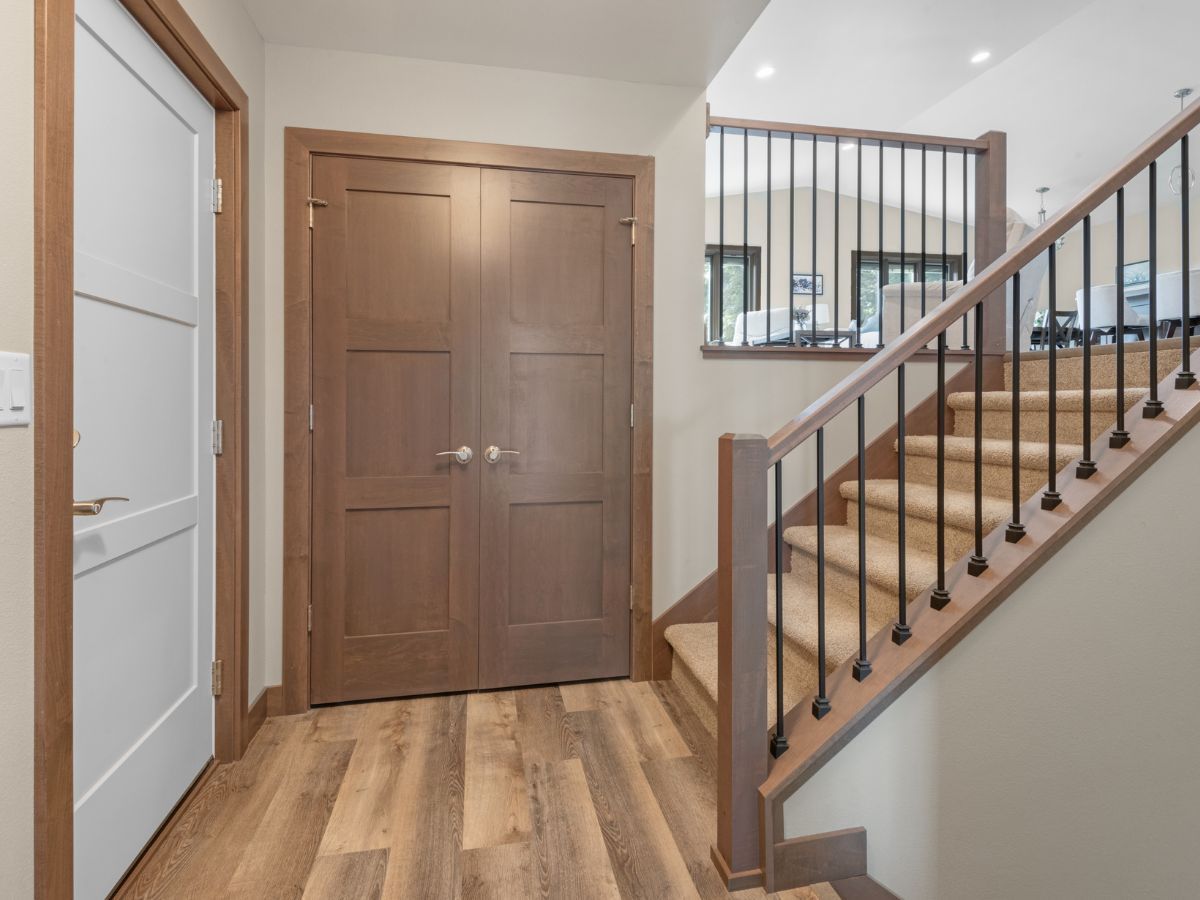 A hallway with wooden floors and stairs leading up to the second floor.
