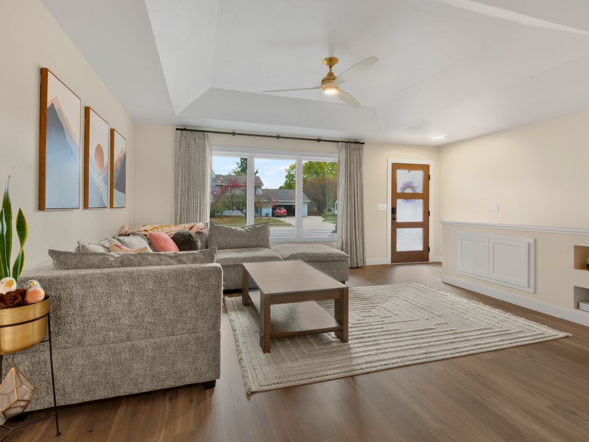 A living room with a couch , coffee table , rug and ceiling fan.