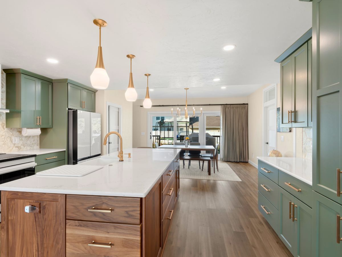 A kitchen with green cabinets and a large island in the middle.