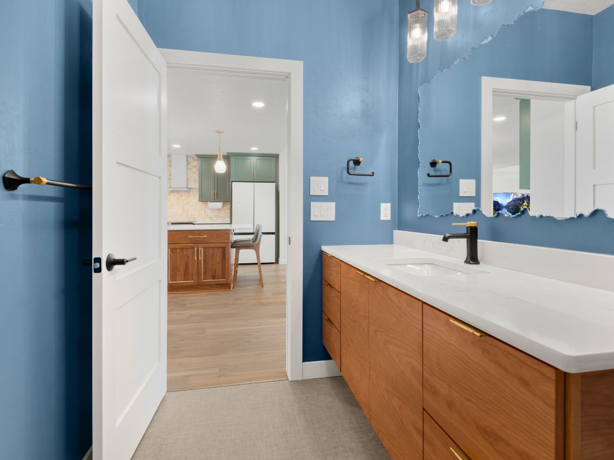 A bathroom with blue walls and wooden cabinets and a large mirror.