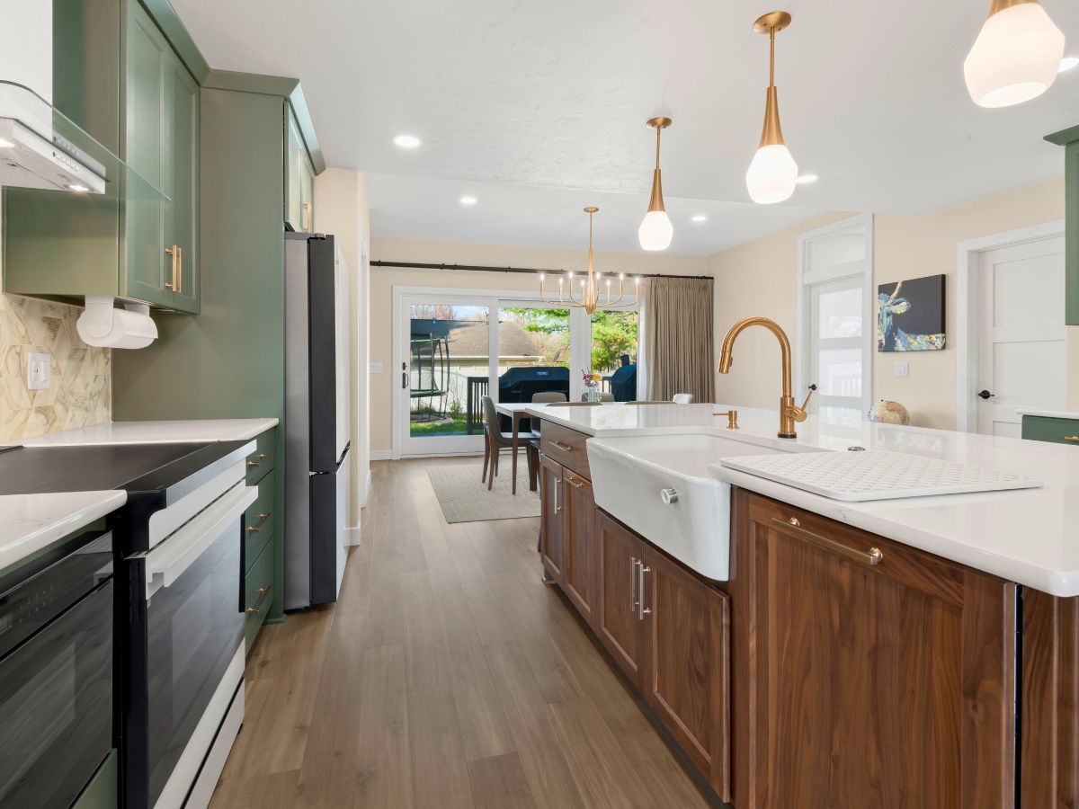 A kitchen with a sink , stove , refrigerator and cabinets.