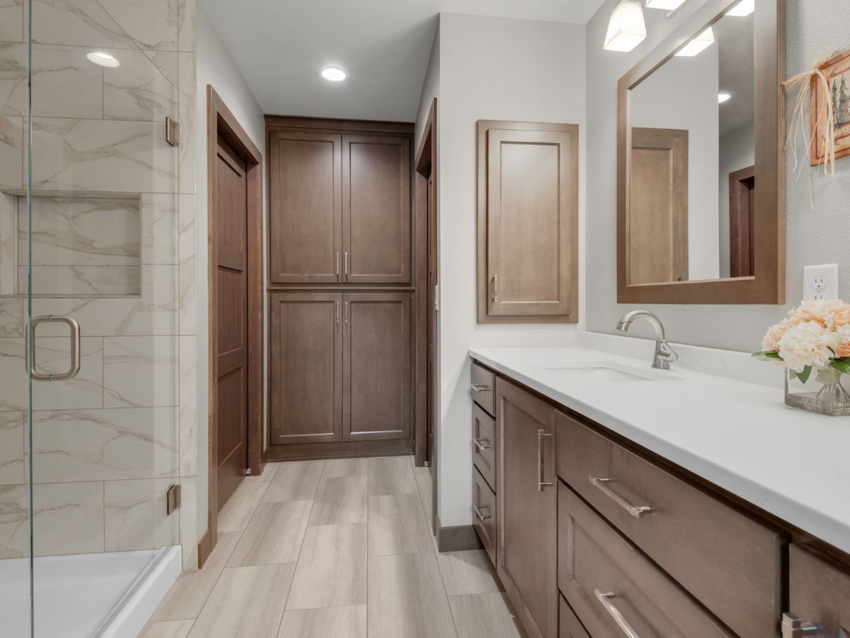 A bathroom with two sinks , a mirror and a walk in shower.