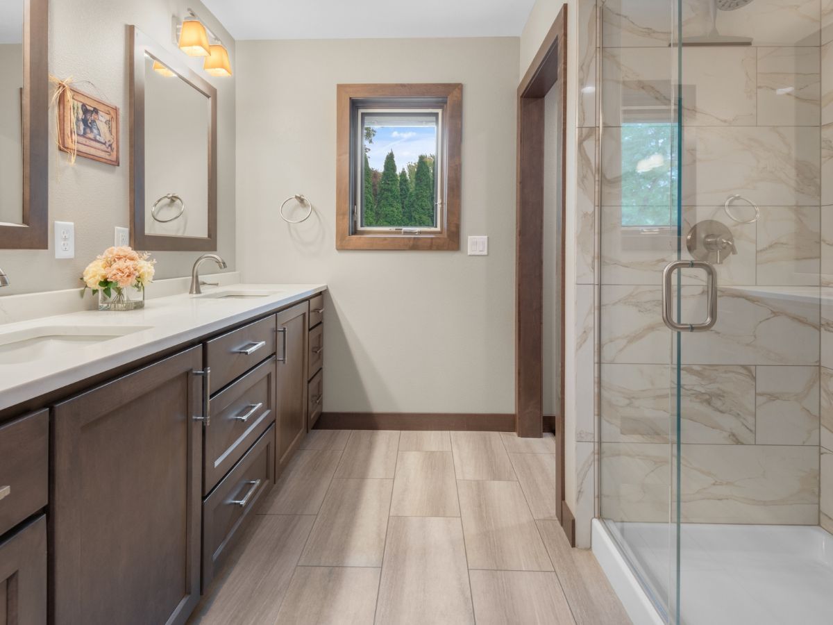 A bathroom with two sinks and a walk in shower.