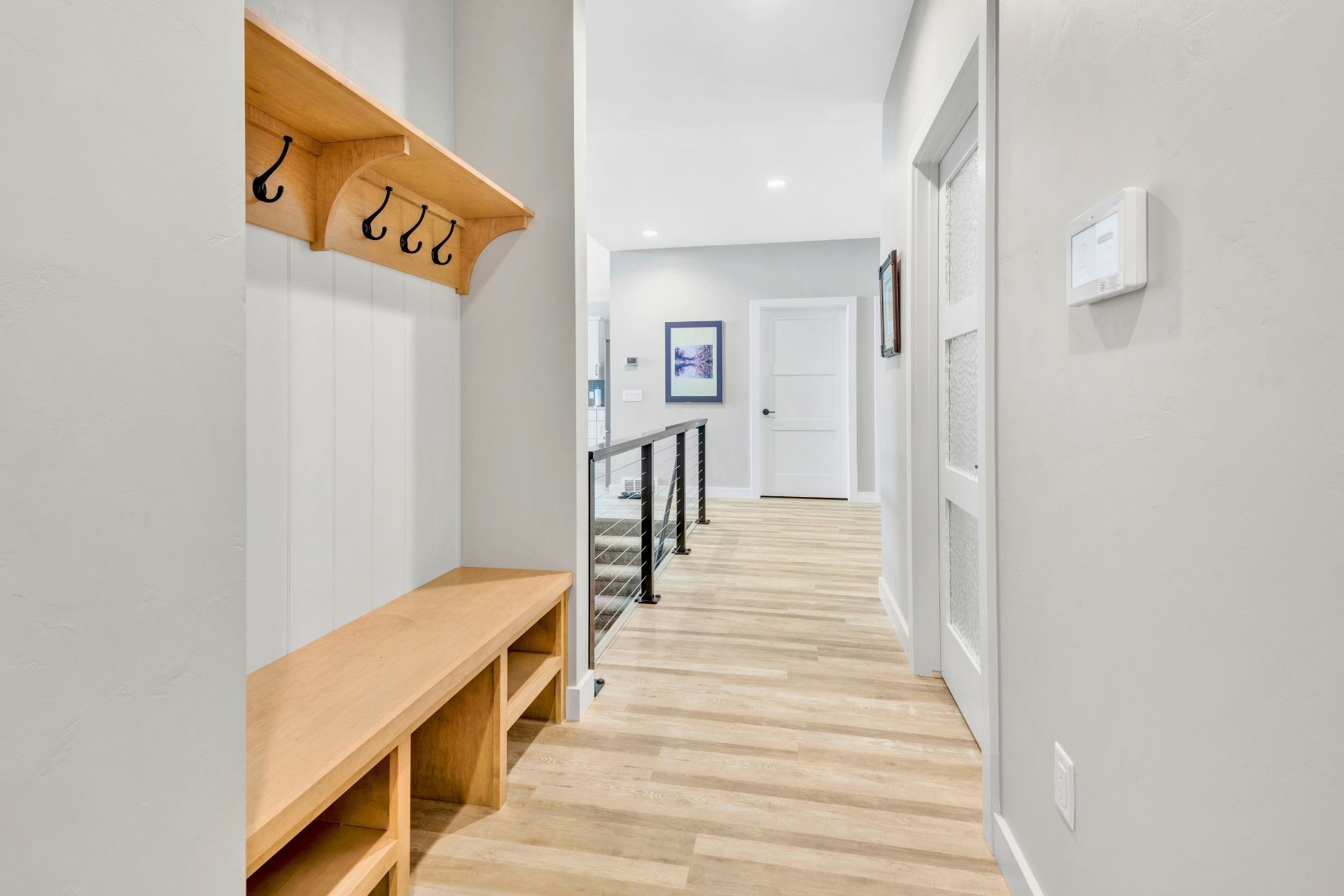 A hallway with a bench and hooks on the wall.