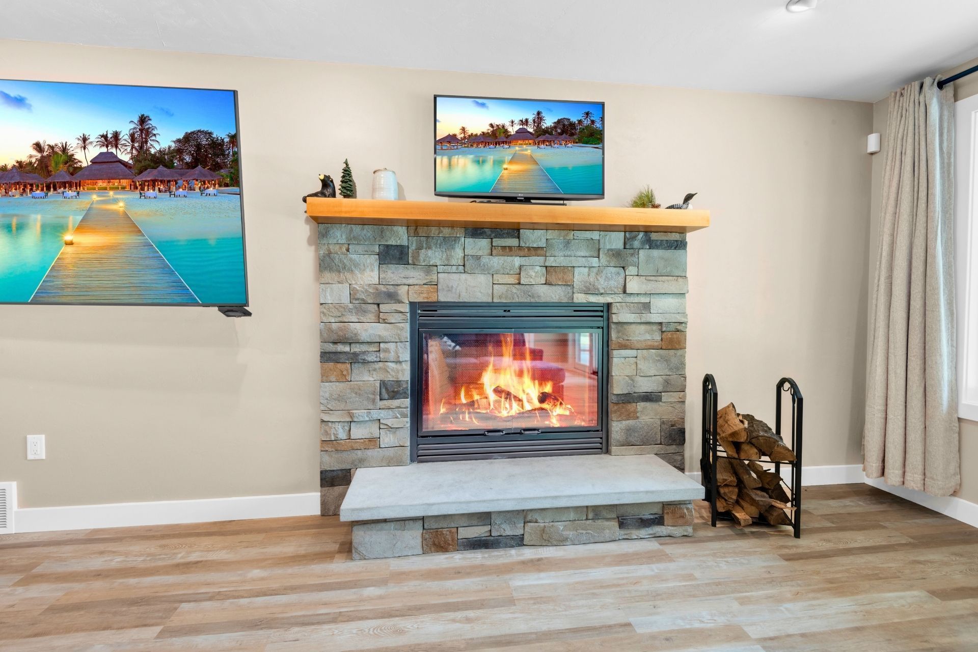 A living room with a fireplace and two televisions