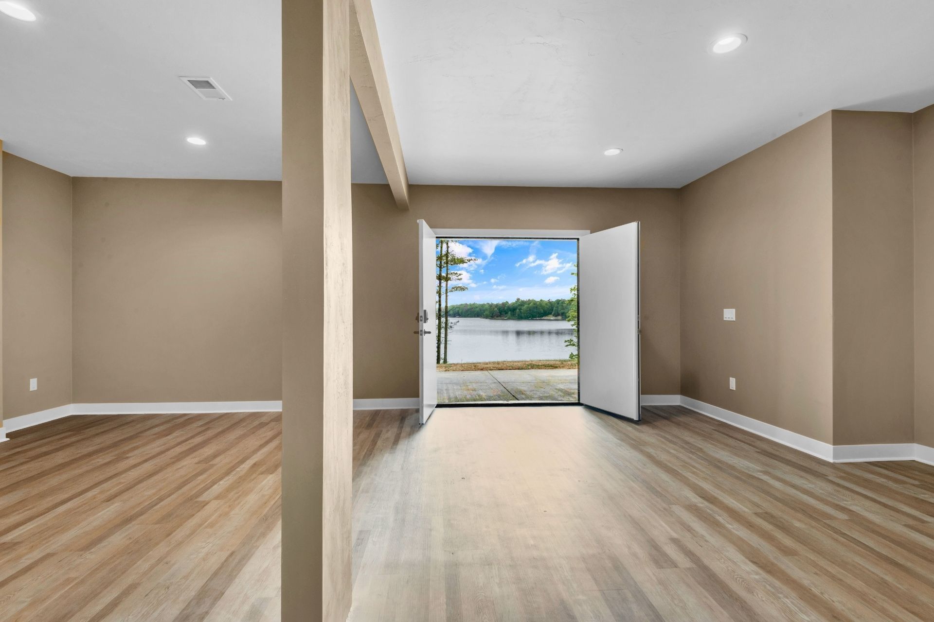 An empty room with hardwood floors and a view of a lake.
